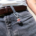 Porte-clés artisanal Gemma en couvert recyclé accroché à un pantalon.