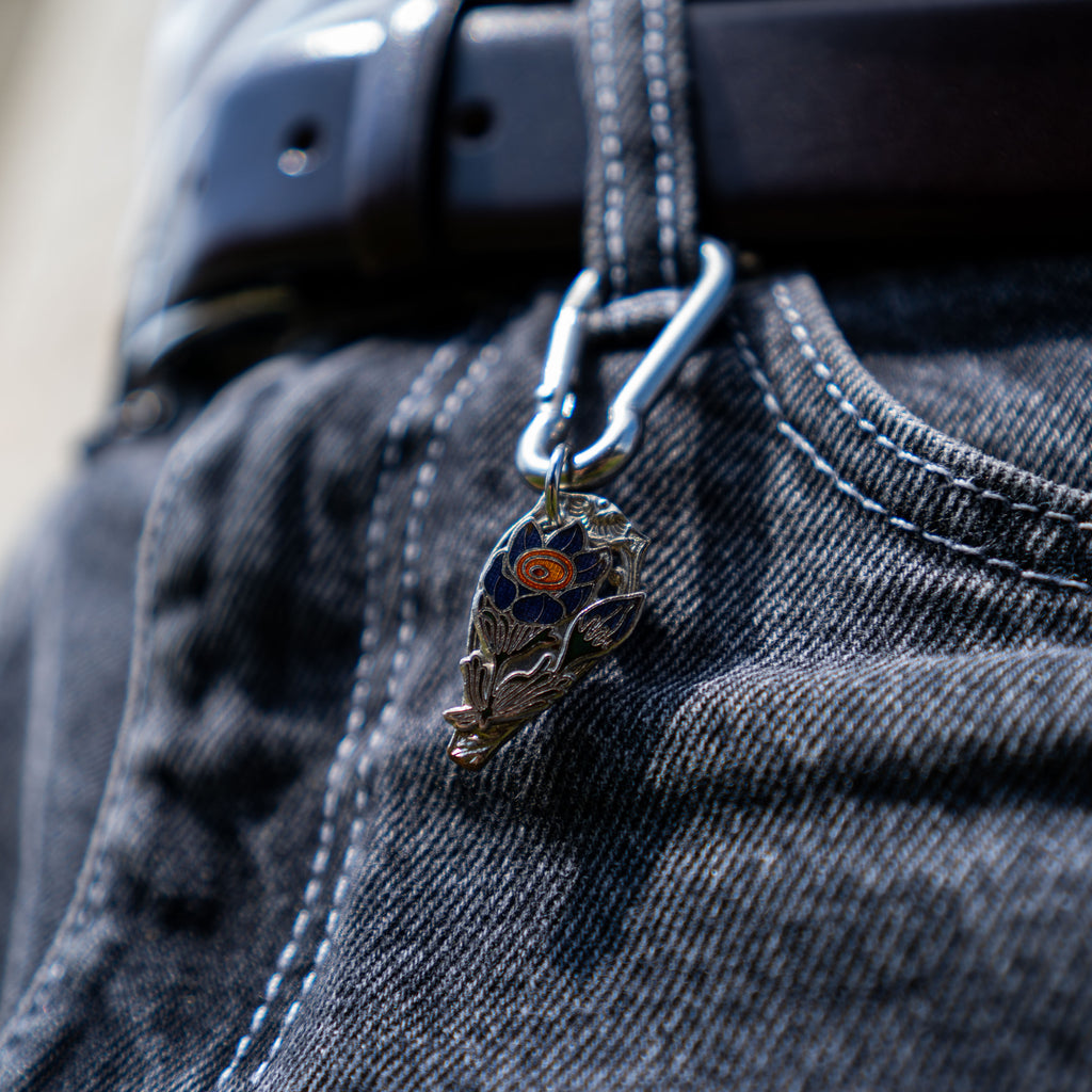Porte-clés artisanal Gemma en couvert recyclé accroché à un pantalon.