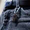 Porte-clés artisanal Gemma en couvert recyclé accroché à un pantalon.