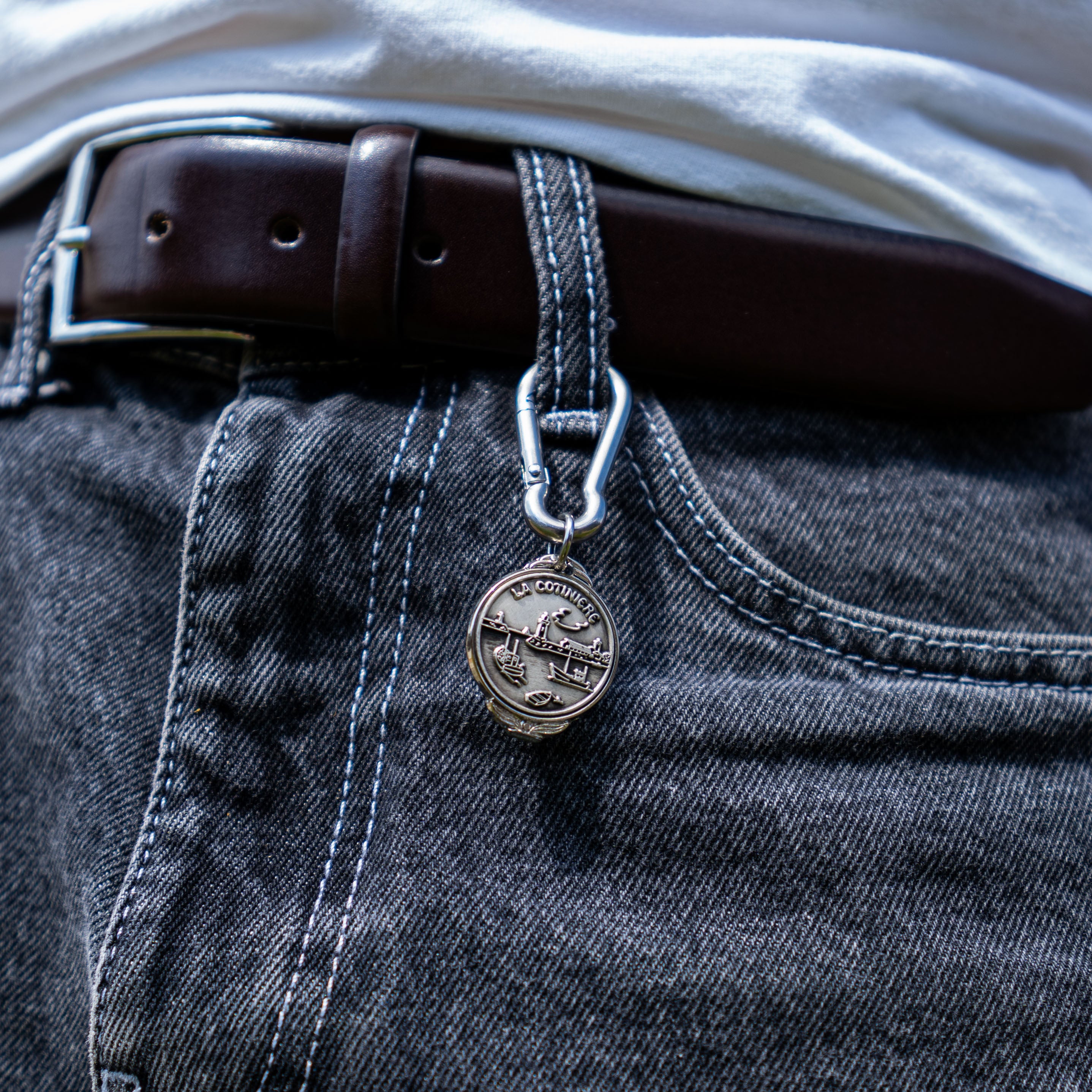 Porte-clés artisanal Gemma en couvert recyclé accroché à un pantalon.