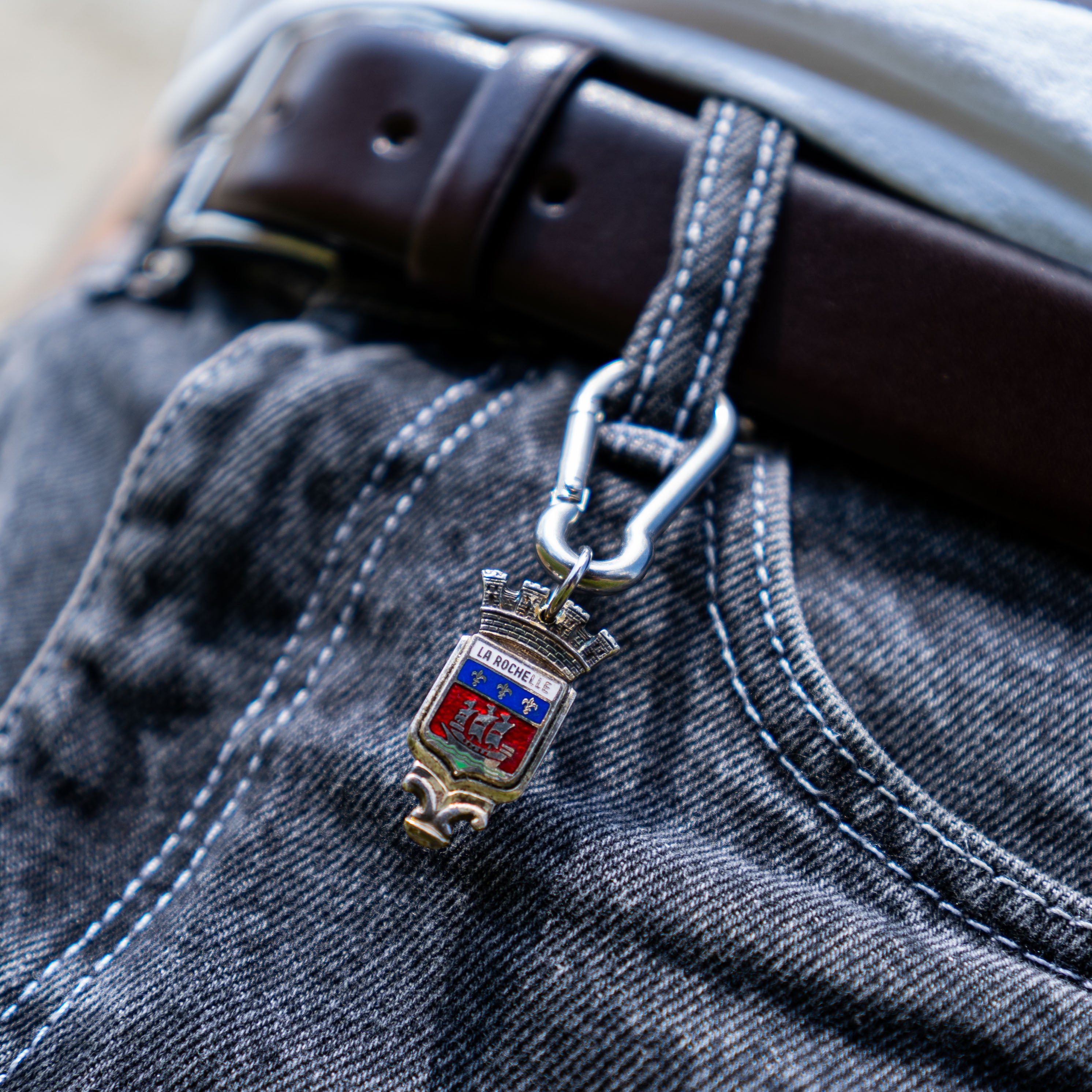 Porte-clés artisanal Gemma en couvert recyclé accroché à un pantalon.